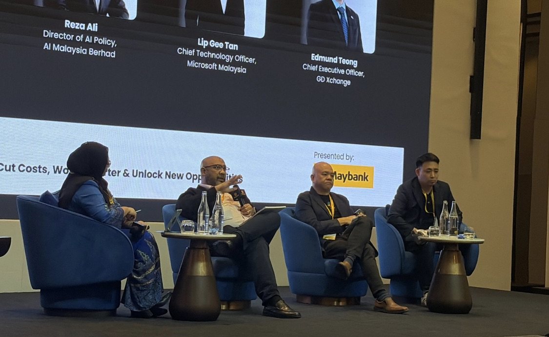 Four panellists seated in blue armchairs on a stage at the Maybank myimpact SME Forum, a screen above them listing the Industry Exchange Panel Session.